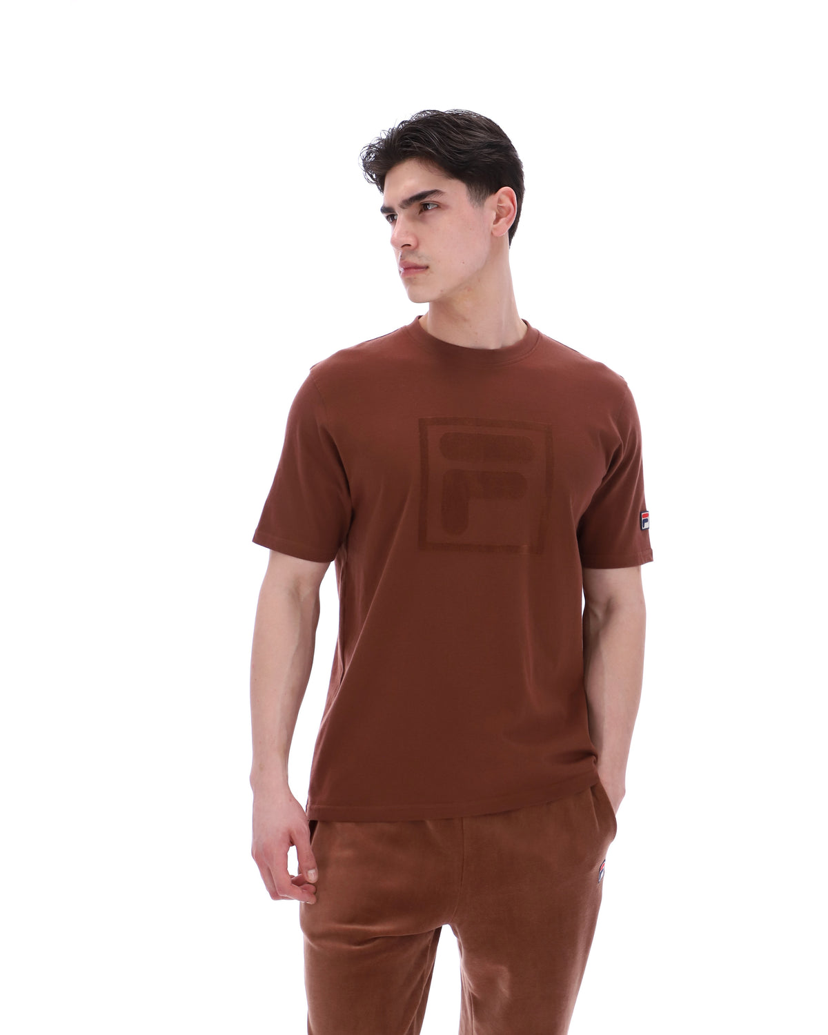 Man wearing a brown t-shirt and pants on a white background