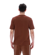 Person wearing a brown t-shirt and pants on a white background