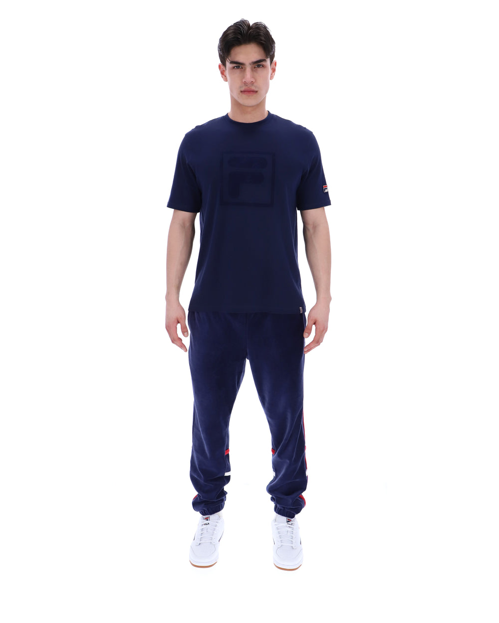 Man wearing a navy blue t-shirt with a FILA logo on the chest and sleeve on a white background