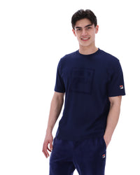 Man wearing a navy blue t-shirt with a FILA logo on the chest and sleeve on a white background
