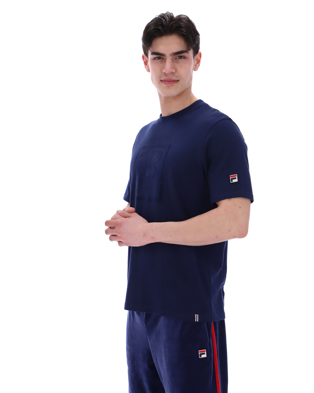 Man wearing a navy blue t-shirt with a FILA logo on the chest and sleeve on a white background