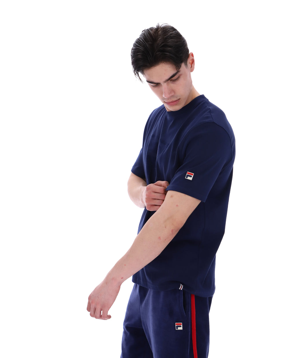 Man wearing a navy blue t-shirt with a FILA logo on the chest and sleeve on a white background
