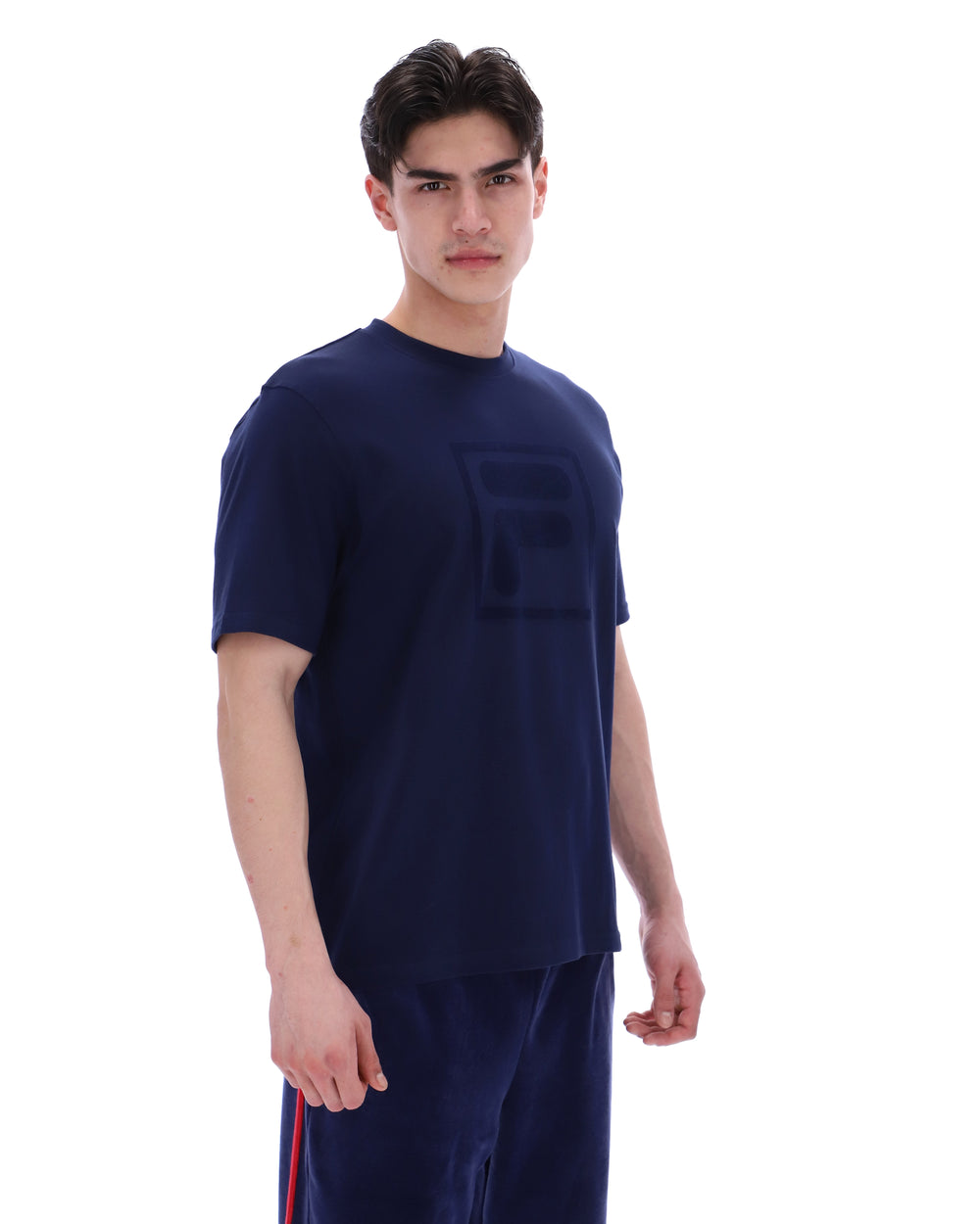 Man wearing a navy blue t-shirt with a FILA logo on the chest and sleeve on a white background