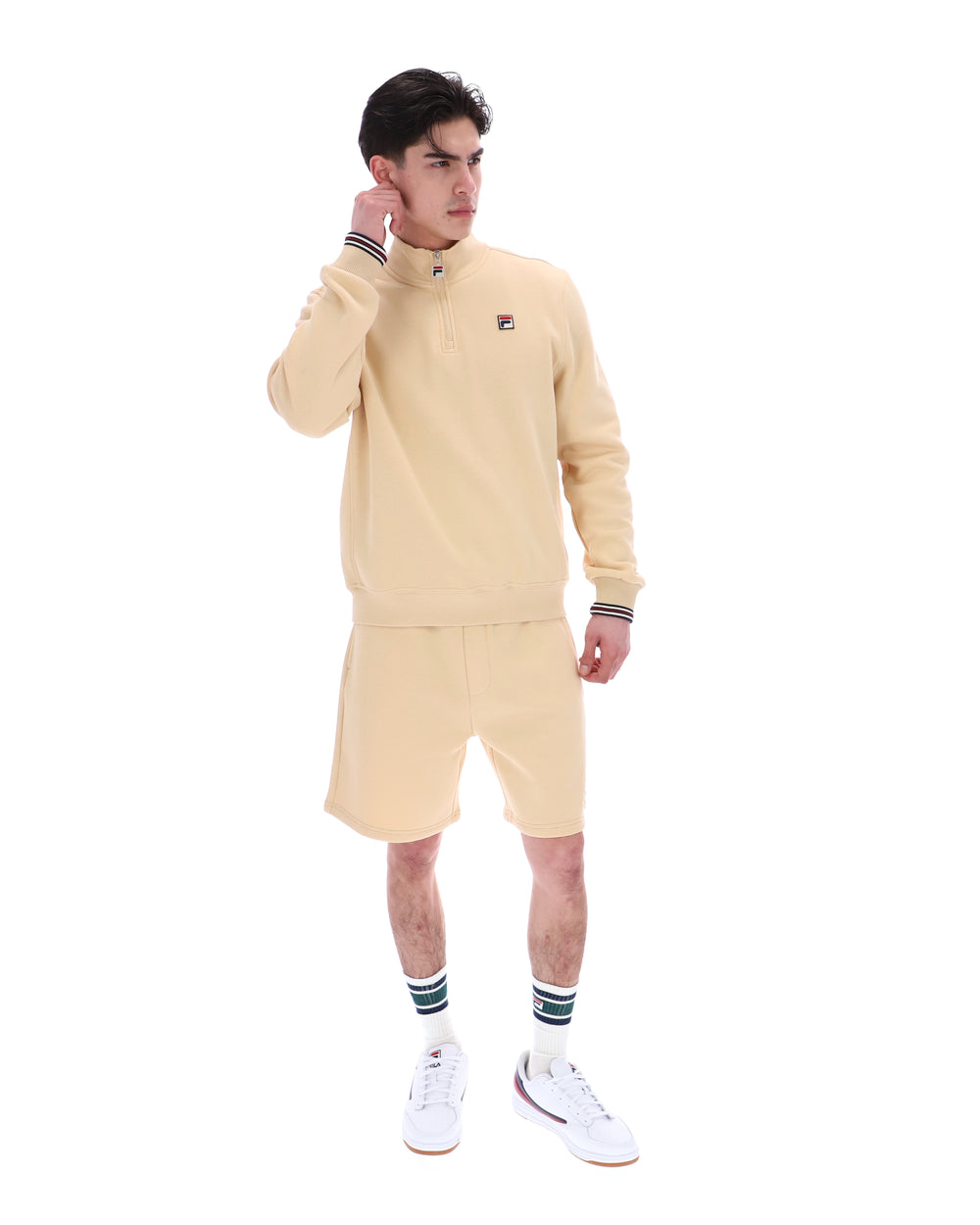 Man wearing a beige tracksuit with a brand logo on a white background
