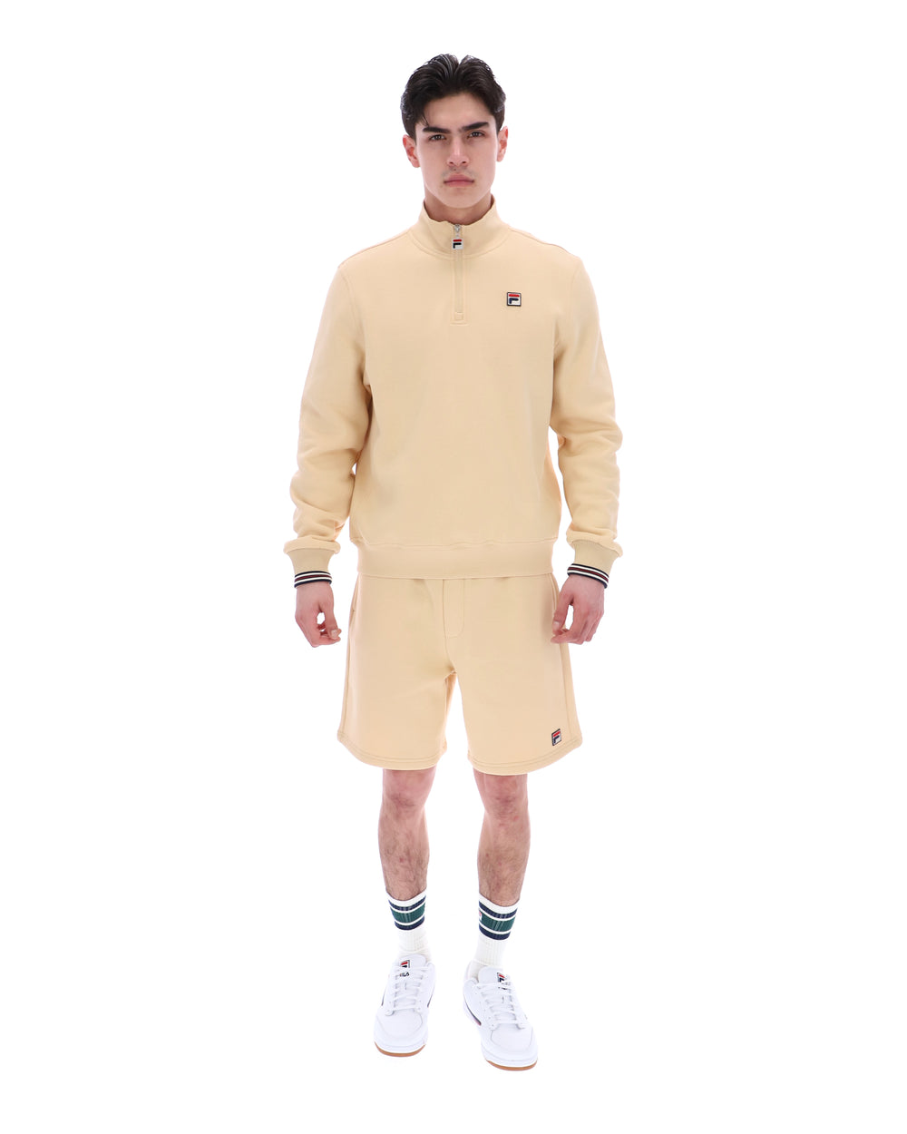 Man wearing a beige tracksuit with a brand logo on a white background