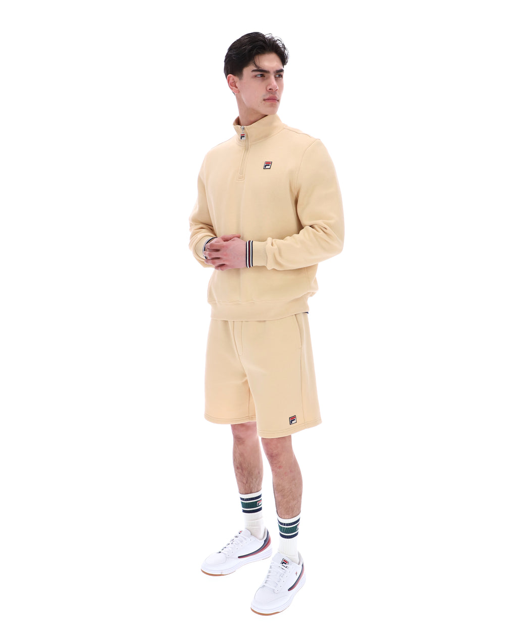 Man wearing a beige tracksuit with a brand logo on a white background