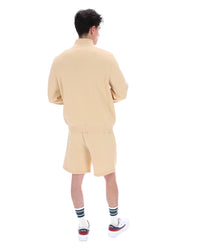 Person wearing a beige tracksuit on a white background