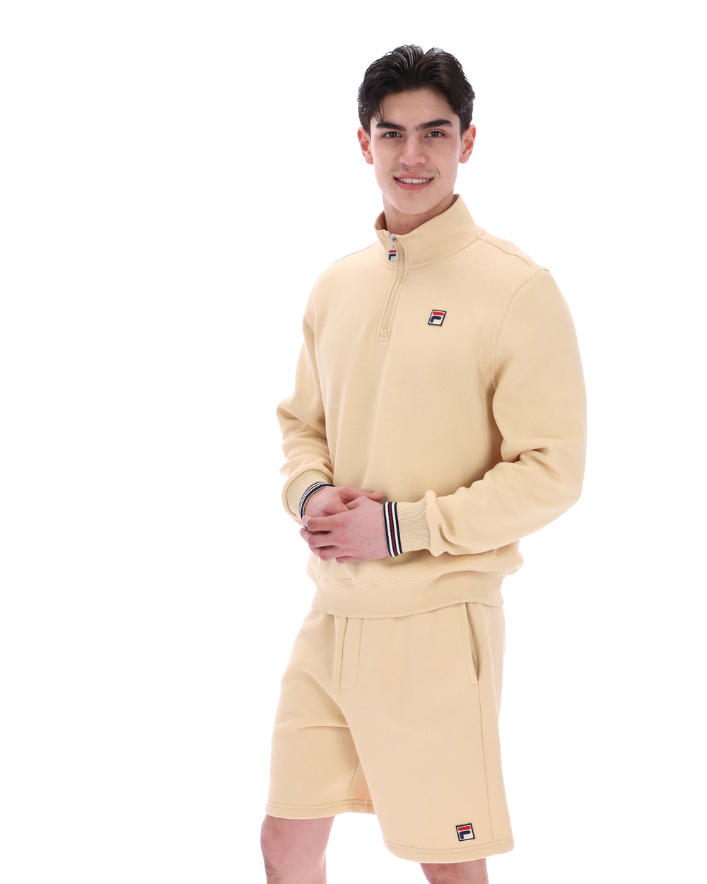 Man wearing a beige tracksuit with a brand logo on a white background