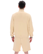 Person wearing a beige outfit with shorts on a white background
