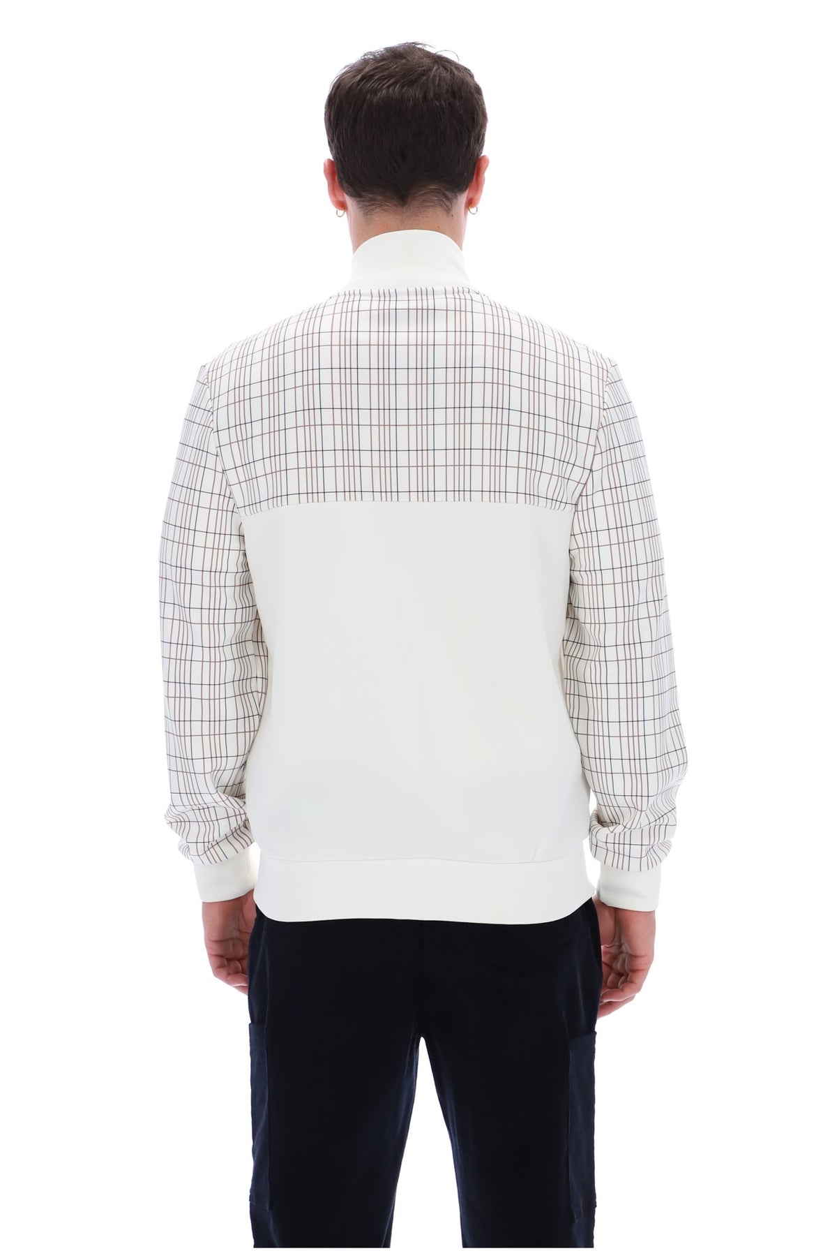 A man viewed from the back wearing a long-sleeve knit sweater with a white and beige plaid upper back and shoulders, a solid white lower back panel, and dark navy pants, against a plain white background.