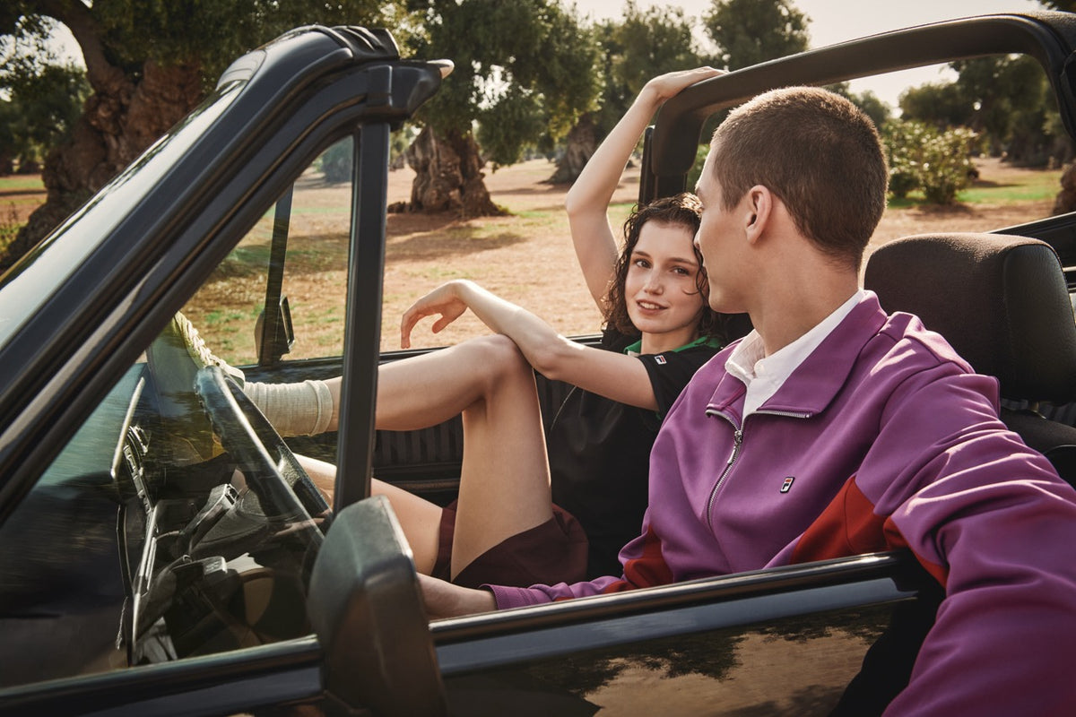 Displays two models one of which is wearing the Purple 'FILA' branded Ventisei Jacket