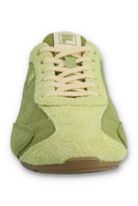 Front view of a FILA Ritmo trainer in green suede, showcasing the pale green textured toe box, contrasting cream laces, and a cream FILA 'F' logo on the tongue against a white background.