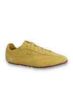 Profile view of a FILA Ritmo trainer in yellow suede, featuring a low-profile silhouette, matching laces, tonal stitching details, a subtle embossed 'F' logo on the side panel, and a slim brown rubber sole against a white background.