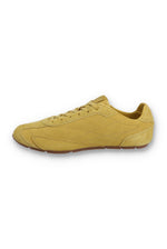 Medial profile view of a FILA Ritmo trainer in yellow suede, showing the unbranded inner side panel with tonal stitching, low-profile design, and a slim brown rubber sole against a white background.