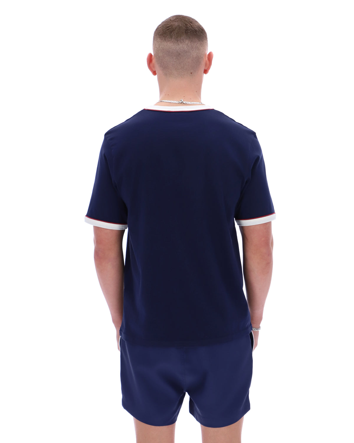 Man wearing a navy blue sports outfit with white trim on a white background