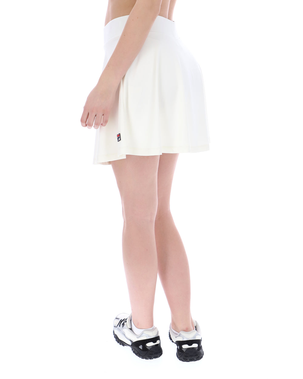 Person wearing a white skirt and black and white shoes on a white background
