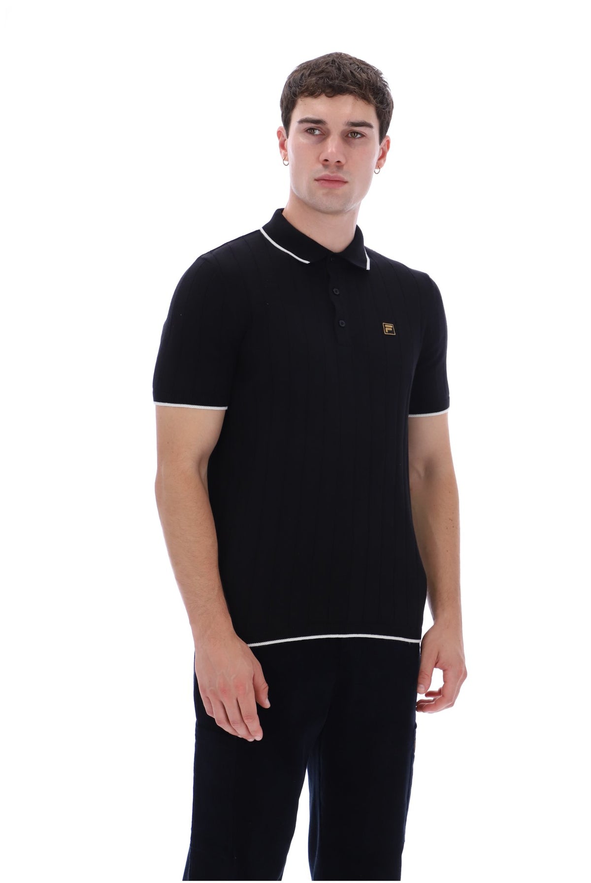 A man wearing a black short-sleeve polo shirt with white piping trim on the collar, sleeve cuffs, and hem, featuring a small gold embroidered logo on the chest, set against a plain white background.