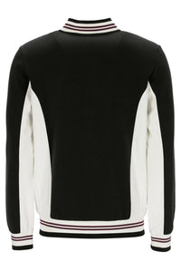 Black and white sweater with striped collar and cuffs on a white background