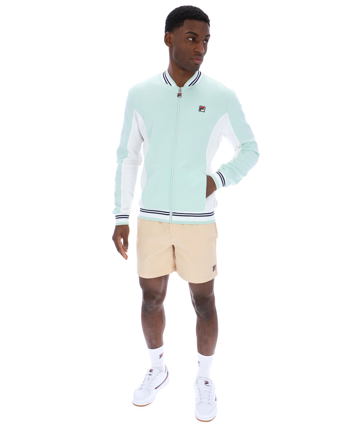 Man wearing a light blue tracksuit with beige shorts on a white background