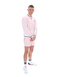 Person wearing a pink tracksuit with a FILA logo, paired with matching shorts on a white background