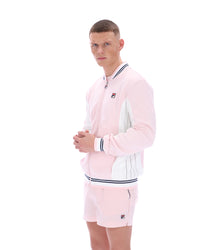 Person wearing a pink tracksuit with a FILA logo, paired with matching shorts on a white background