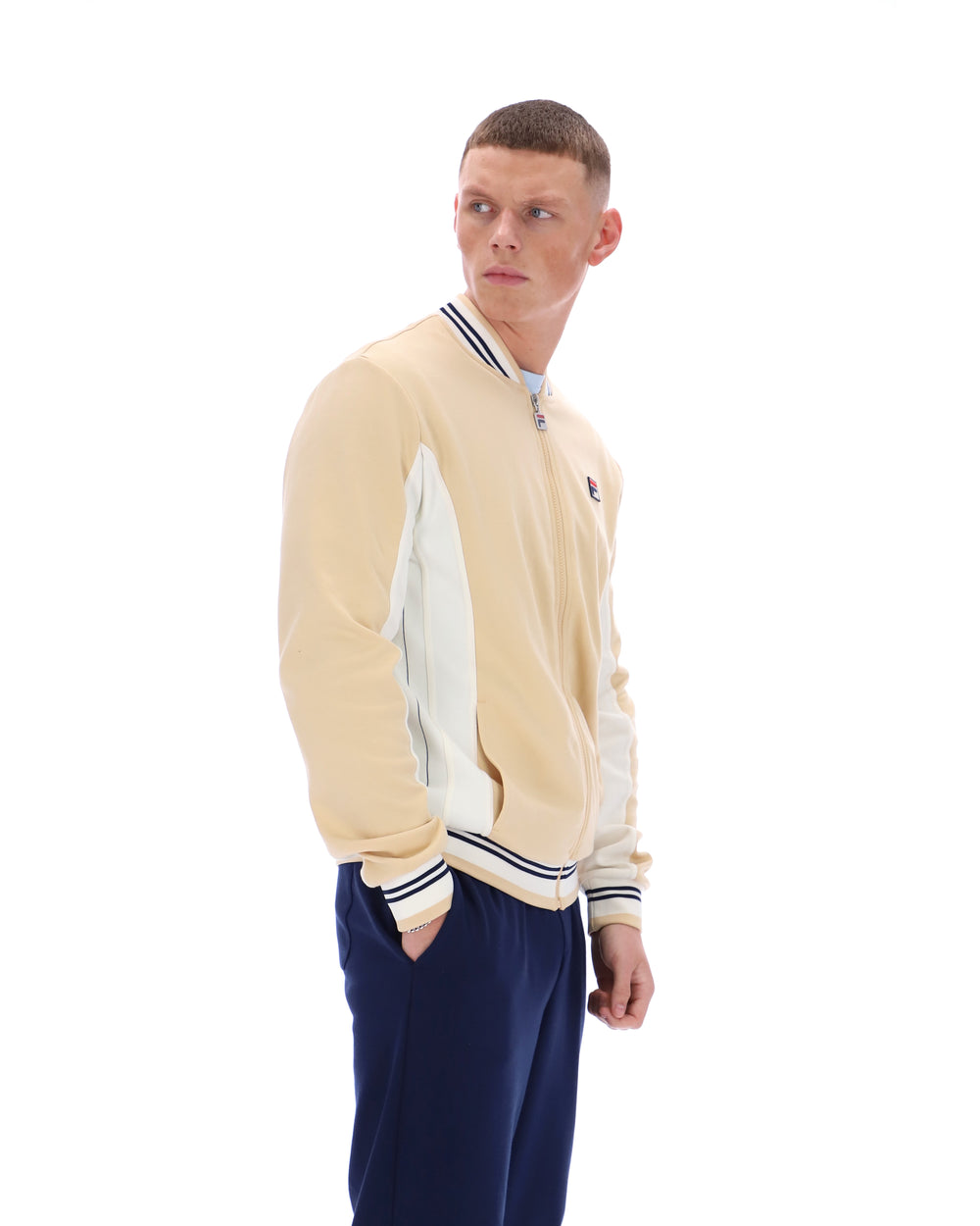 Man wearing a beige and navy varsity jacket on a white background