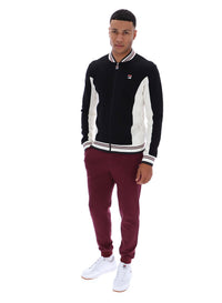 Man wearing a black and white jacket with maroon pants on a white background