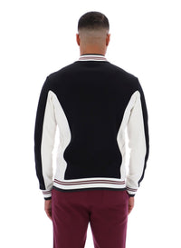 Person wearing a black and white varsity jacket on a white background