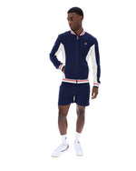 Man wearing a navy tracksuit with white accents on a white background