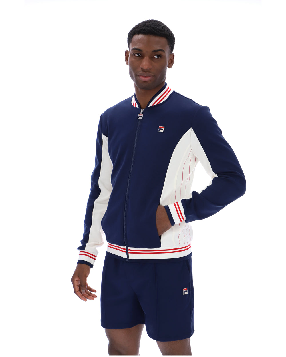 Man wearing a navy tracksuit Jacket and shorts with white accents on a white background