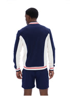 Man wearing a navy tracksuit jacket and shorts with white accents on a white background