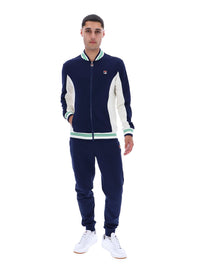 Man wearing a navy and white track top with a FILA logo on the chest, paired with matching joggers, on a white background