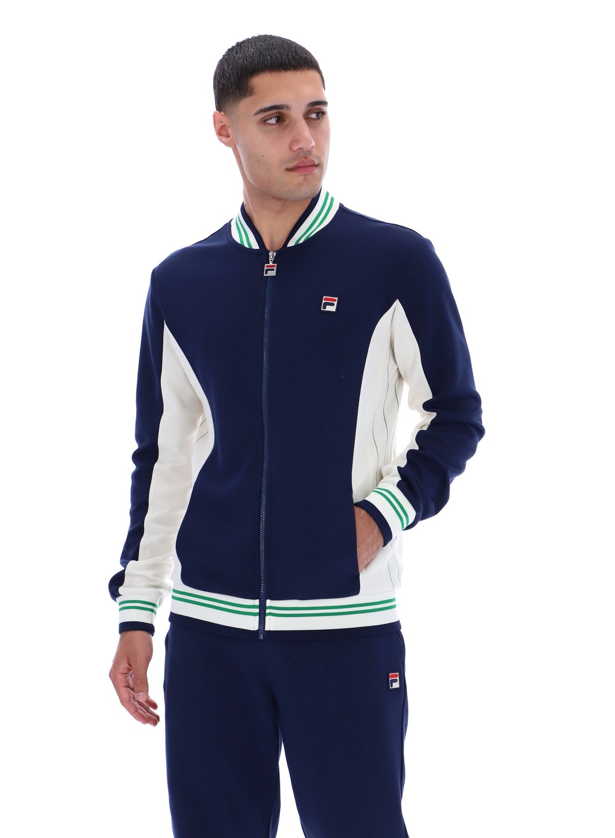 Man wearing a navy and white track top with a FILA logo on the chest, paired with matching joggers, on a white background