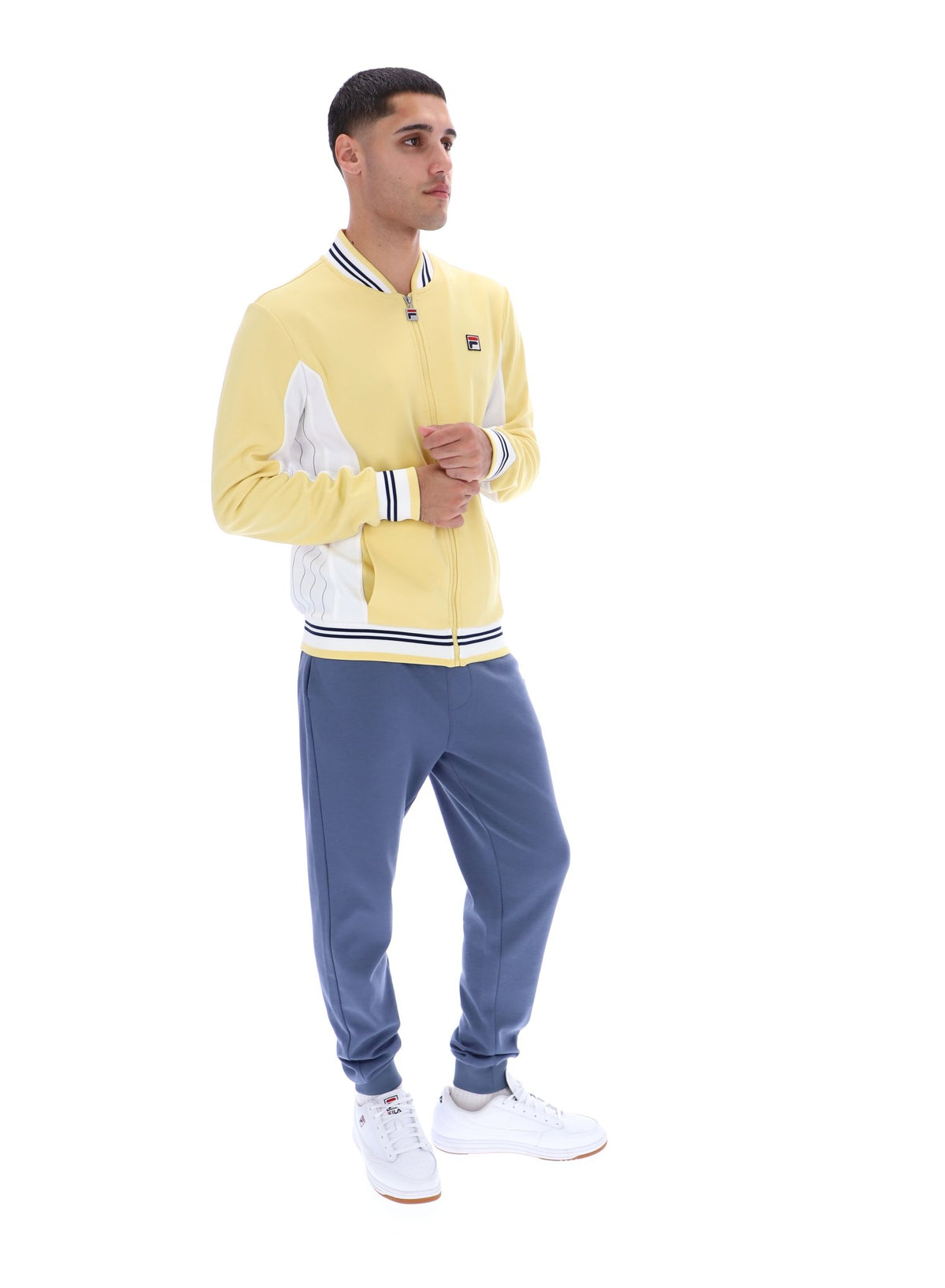 Man wearing a yellow and white tracksuit with blue pants on a white background