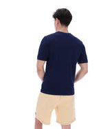 Man wearing a navy blue t-shirt and beige shorts on a white background