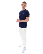Man wearing a navy t-shirt and white pants on a white background