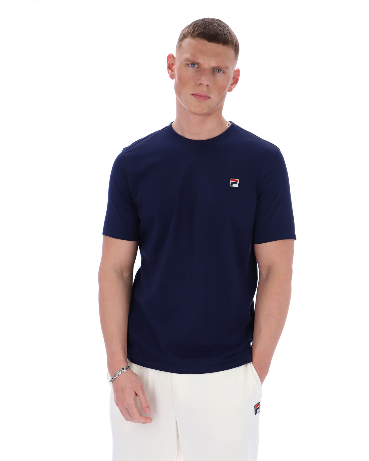 Man wearing a navy blue t-shirt with a small logo on a white background