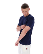Man wearing a navy blue t-shirt with a logo on a white background