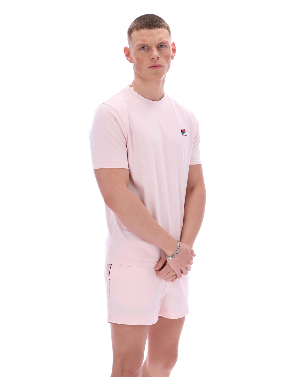 Man wearing a light pink t-shirt and shorts set on a white background