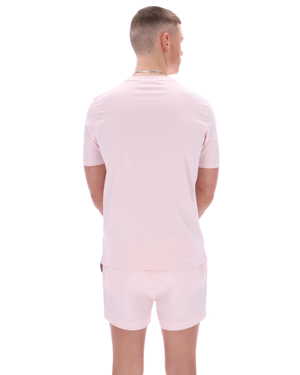 Person wearing a light pink t-shirt and shorts set on a white background