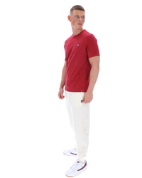 Man wearing a red polo shirt and white pants on a white background
