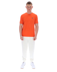 Man wearing an orange t-shirt and white pants on a white background