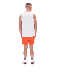Man wearing a white tank top and orange shorts on a white background