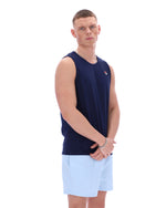 Man wearing a navy sleeveless shirt and light blue shorts on a white background