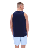 Man wearing a navy sleeveless shirt and light blue shorts on a white background