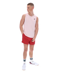 Man wearing a light pink sleeveless shirt and red shorts on a white background