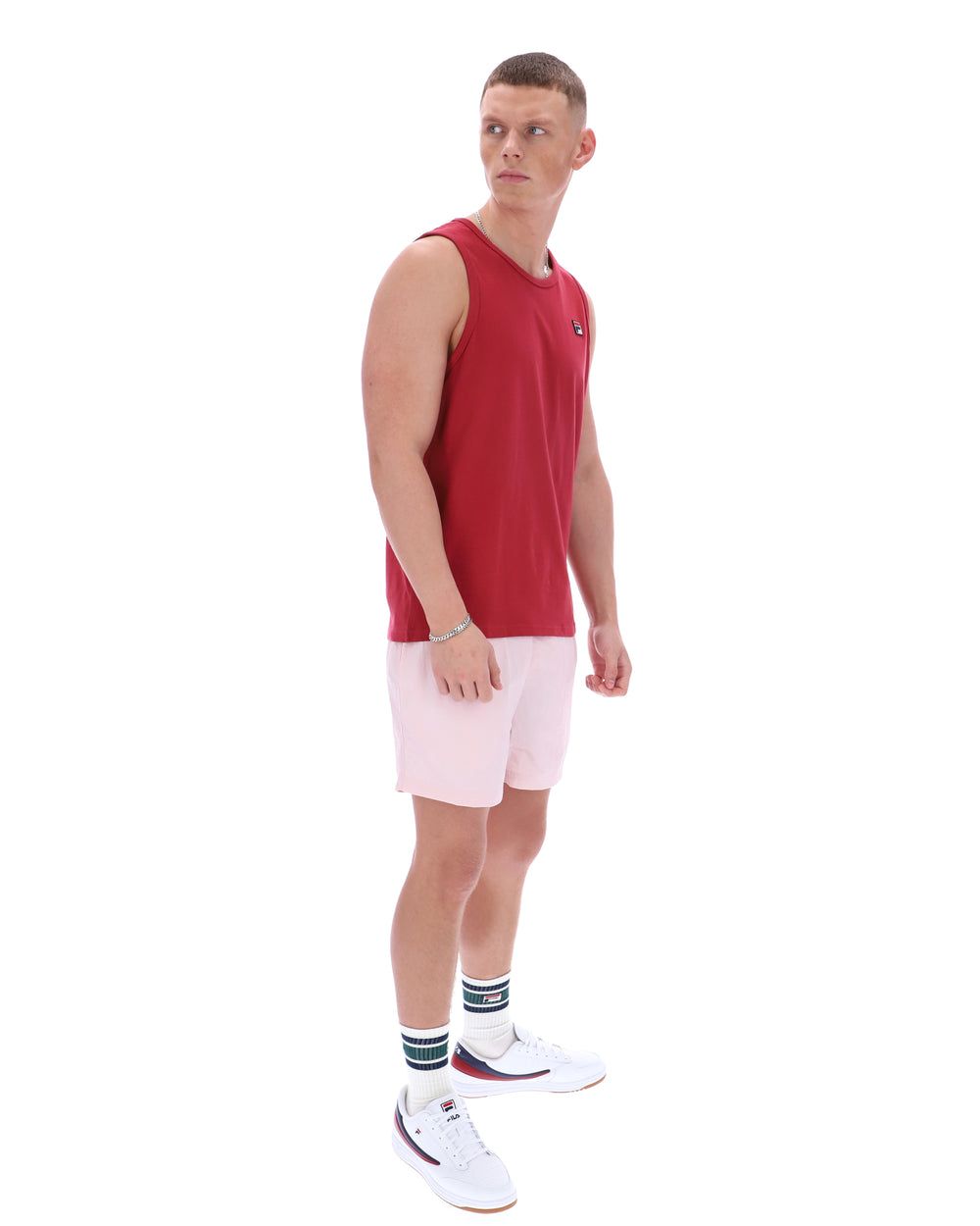Man wearing a red sleeveless shirt and pink shorts on a white background