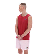 Man wearing a red sleeveless shirt and pink shorts on a white background