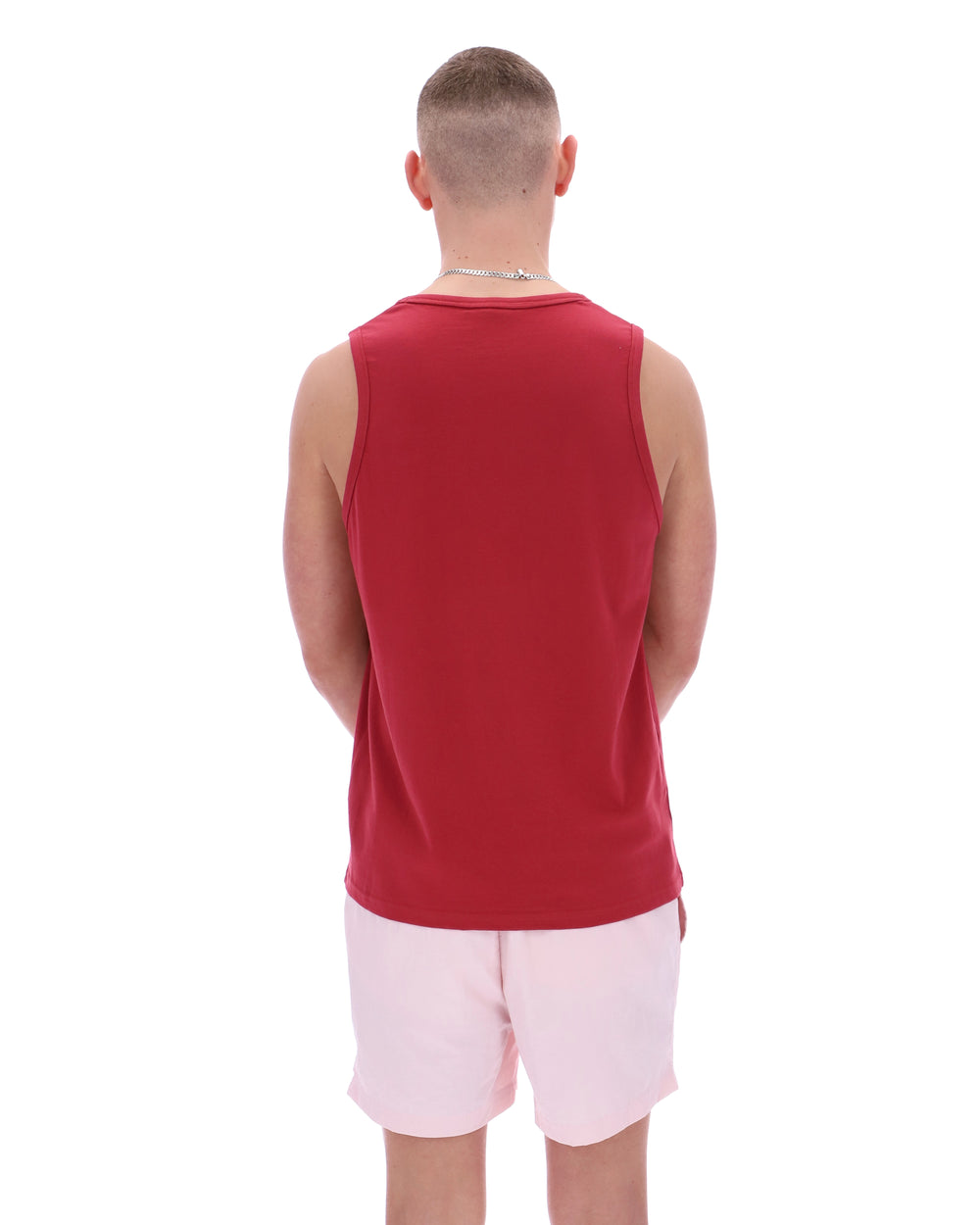 Person wearing a red sleeveless shirt and white shorts on a white background