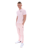 Man wearing a pink t-shirt with a FILA logo on the chest and matching trousers on a white background